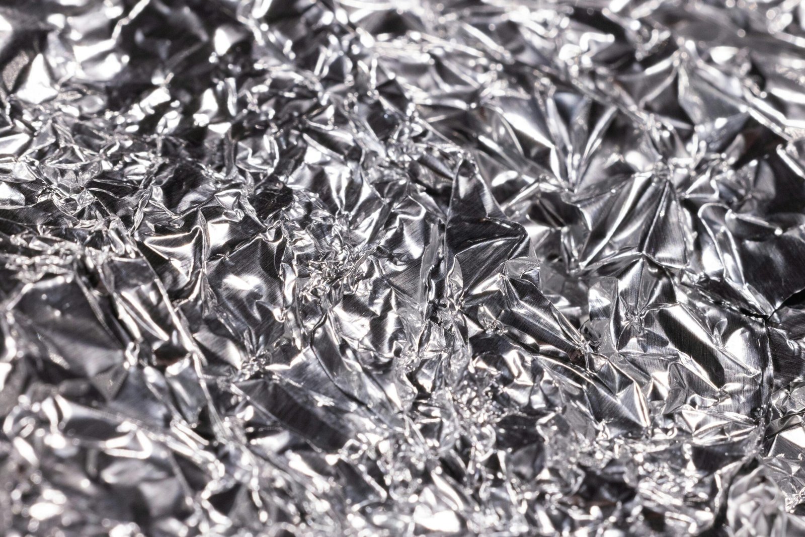 Detailed macro shot of crumpled aluminum foil, showcasing texture and shine.