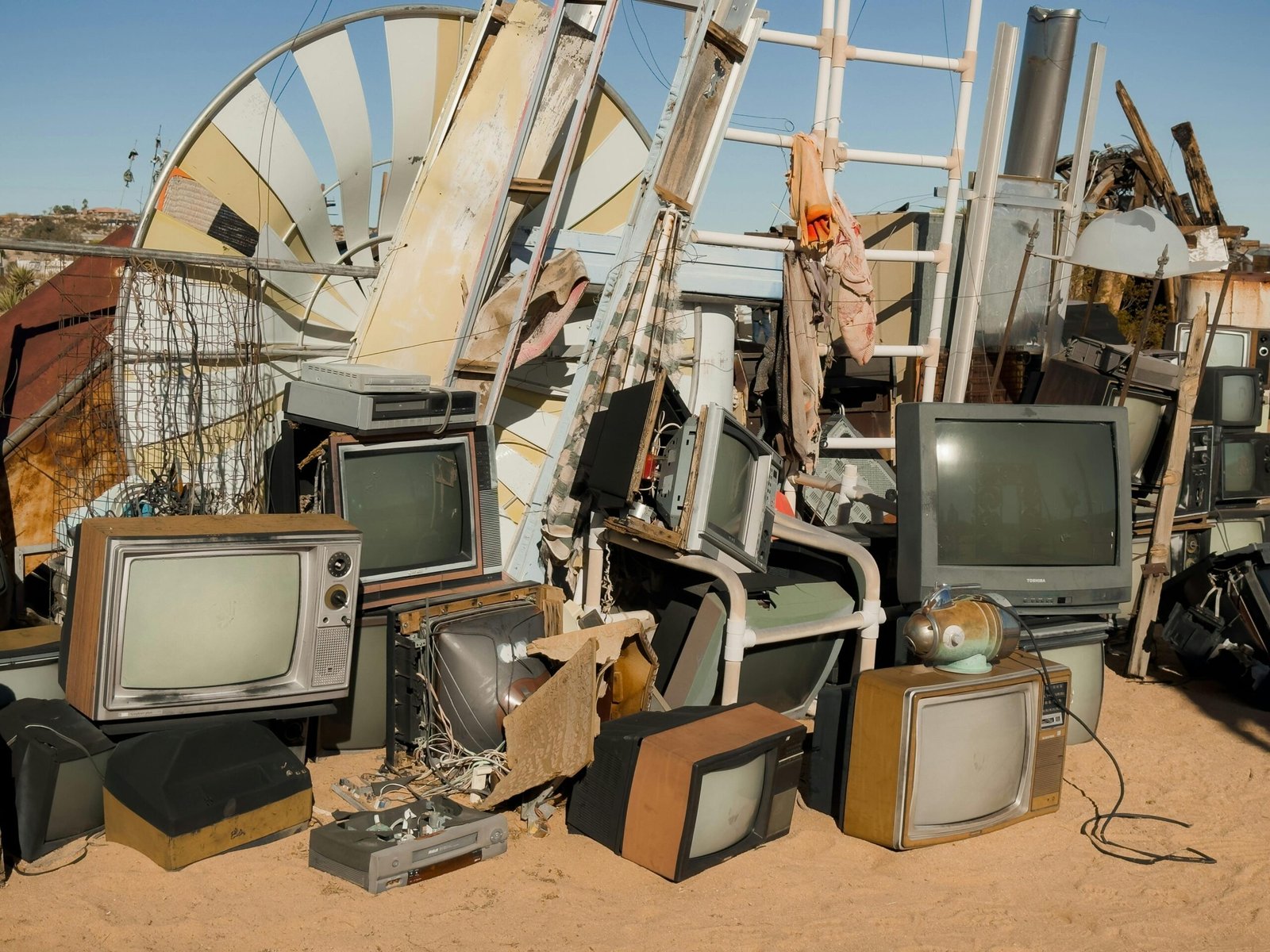 A pile of vintage televisions and scrap metal in the Joshua Tree desert.